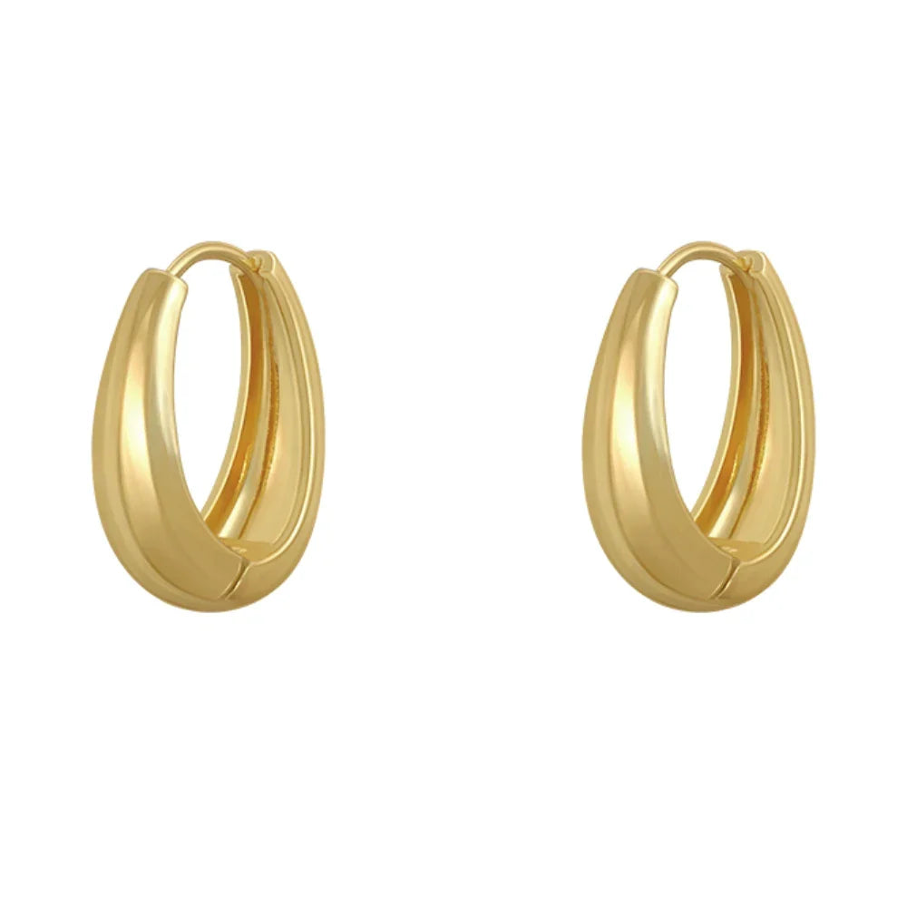 Damen trägt elegante Gold Creolen, modische Edelstahl Ohrringe als zeitloses Accessoire für den Look.