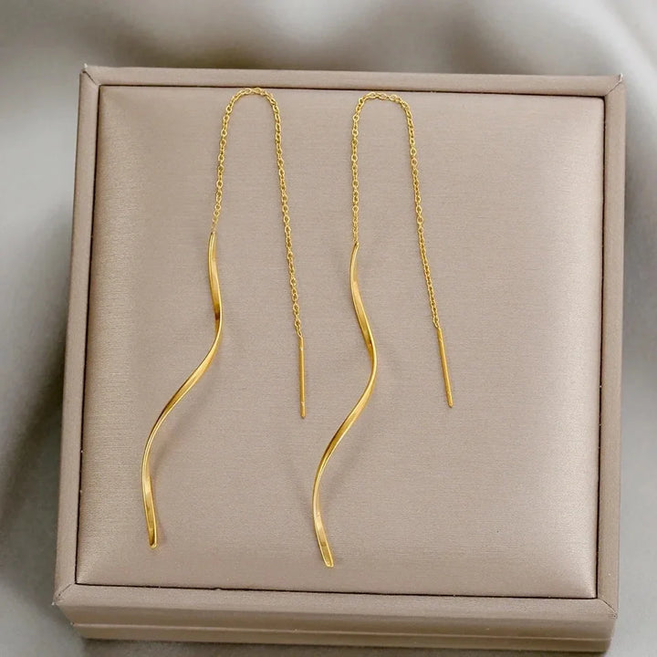 Detailaufnahme: Wellenförmige Damenohrringe mit feinen Quasten, moderner Modeschmuck.