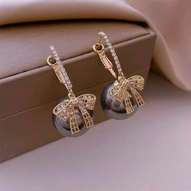 Detailaufnahme von Weihnachts-Perlenohrringen mit roten Satinschleifen, eleganter Damenschmuck.