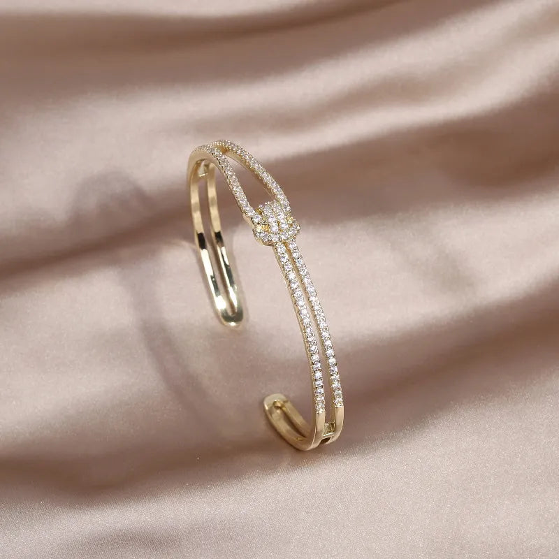 Stilvoller Damen Armreif mit funkelnden Kristallen und elegantem Goldknoten Design.