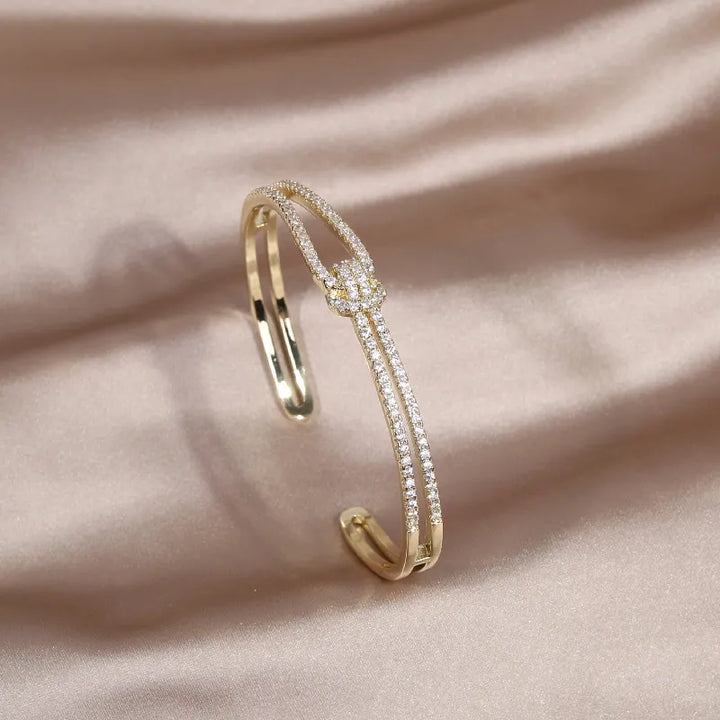 Stilvoller Damen Armreif mit funkelnden Kristallen und elegantem Goldknoten Design.