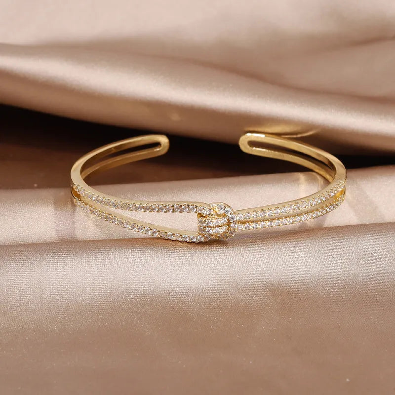 Glänzender Schmuck für Damen: ein edler Armreif mit Kristallen und einem Goldknoten.