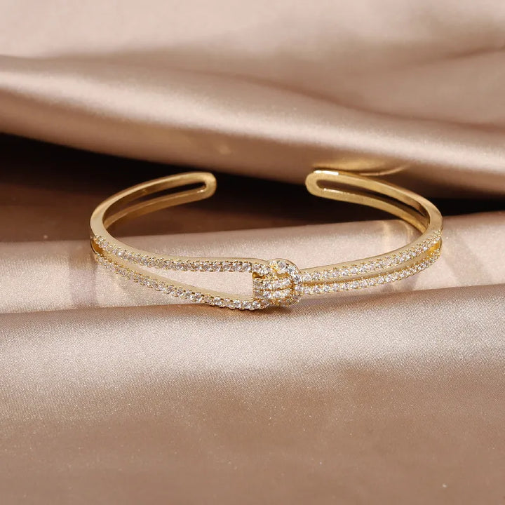 Glänzender Schmuck für Damen: ein edler Armreif mit Kristallen und einem Goldknoten.