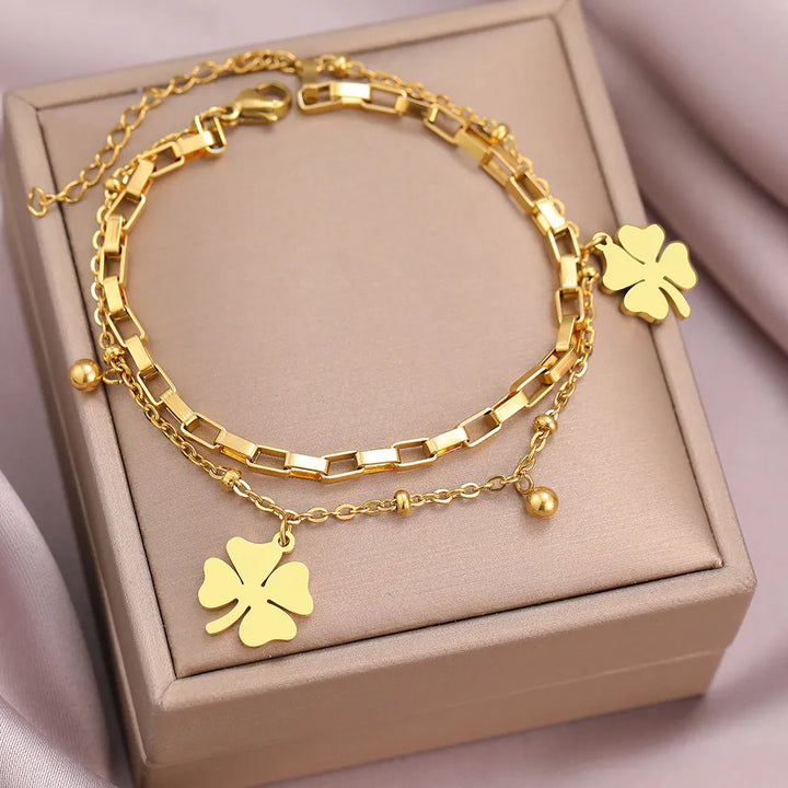 Detailansicht des filigranen Kleeblatt-Anhängers am Damenarmband in glänzendem Gold und Silber.