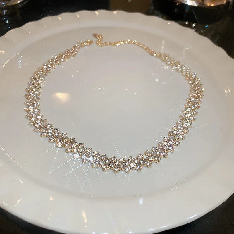 Glamouröse Statement-Halskette für Damen mit goldenem, geometrischem Design und glitzernden Gala-Strasssteinen.