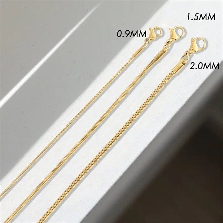 Nahaufnahme eines minimalistischen Damen- und Herrenarmbands, Schlangenschließe als Detail, glänzendes Metall.