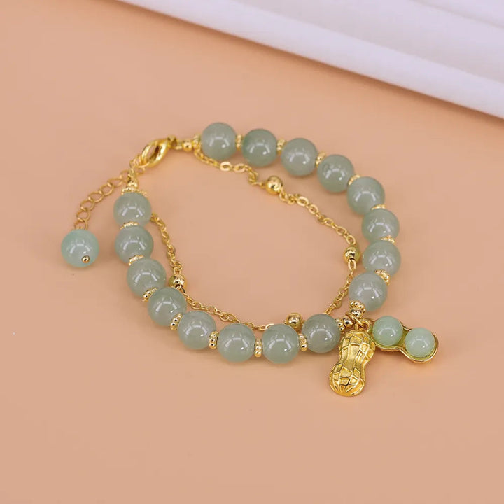 Damen Armband mit runden Hetien Jade Perlen, Goldakzent und Blatt-/Erdnuss-Anhänger, aus Edelstahl.