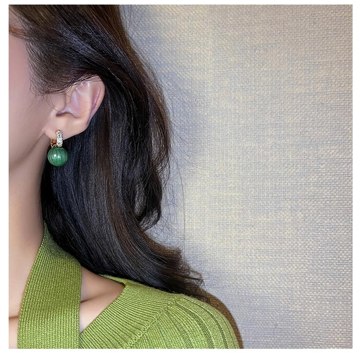 Vergoldete Perlenohrringe für Damen mit glänzenden grünen Perlen. Klassischer, eleganter Damenschmuck.