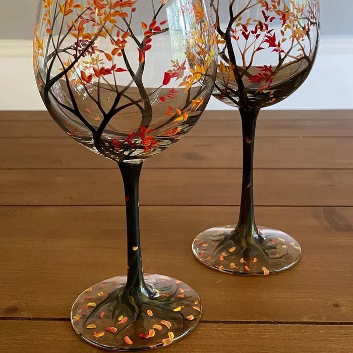 Handbemalte Weingläser mit Jahreszeiten-Baum auf gedecktem Tisch, schaffen festliche Atmosphäre & Tischkultur.