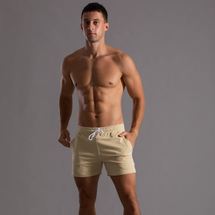 Model in bequemen Herren Badeshorts am Strand, schnelltrocknend, für aktive Freizeit.