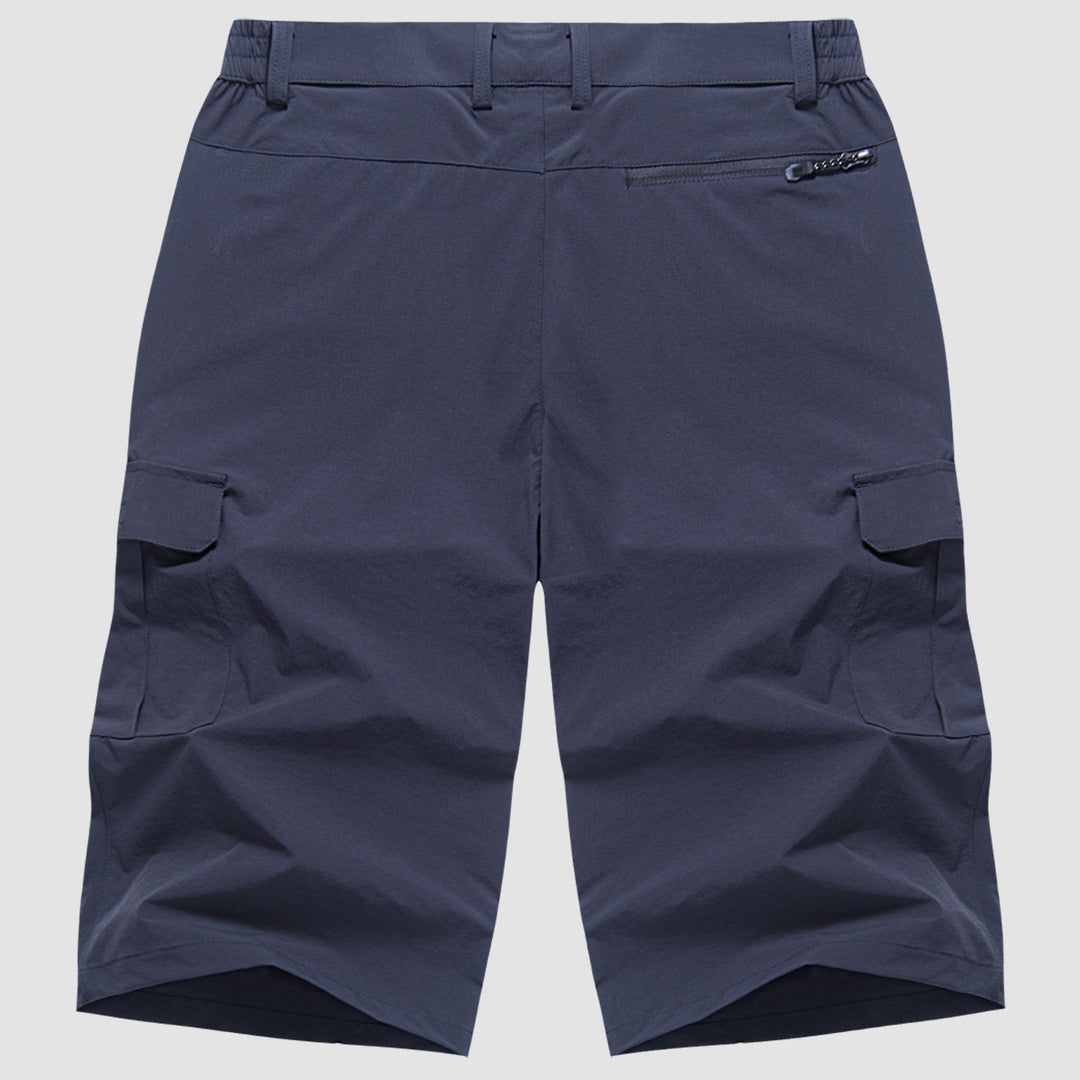 Mann trägt dunkle, bequeme Herren Cargo Shorts beim sommerlichen Wandern in der Natur.