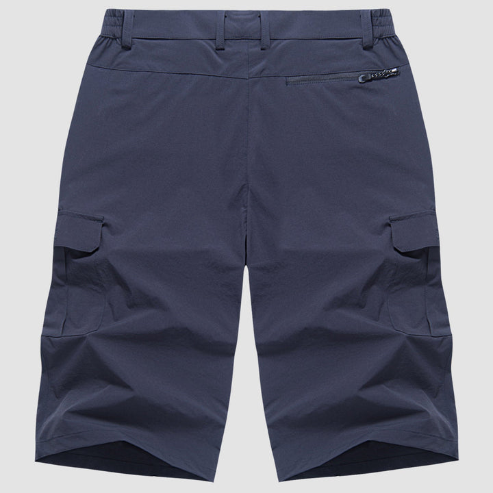 Mann trägt dunkle, bequeme Herren Cargo Shorts beim sommerlichen Wandern in der Natur.