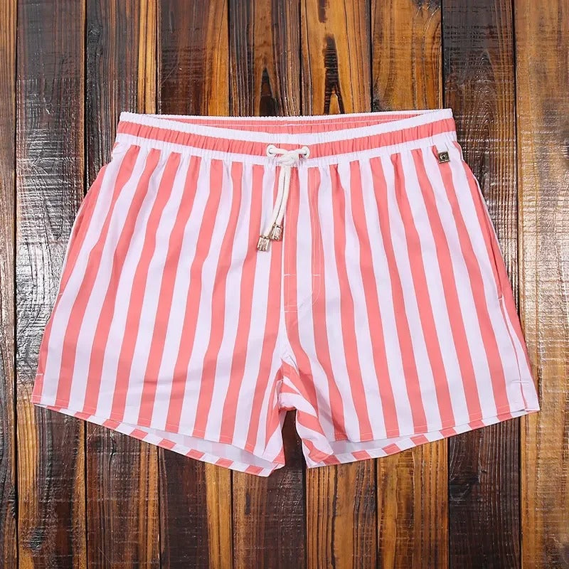 Modell trägt gestreifte Herren Badeshorts am Strand, stilvoll und komfortabel. Perfekte Badebekleidung.