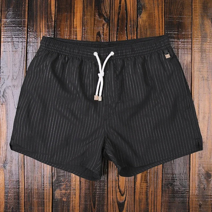 Gefaltete gestreifte Badeshorts für Herren, bereit für den Urlaub. Schnelltrocknend & leicht.