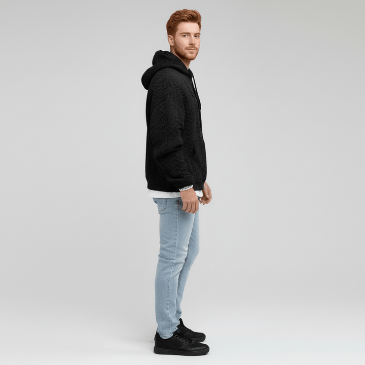Mann trägt bequemen Logan Zopfmuster Kapuzenpullover. Stilvoller Strick Hoodie für Herbst & Winter.