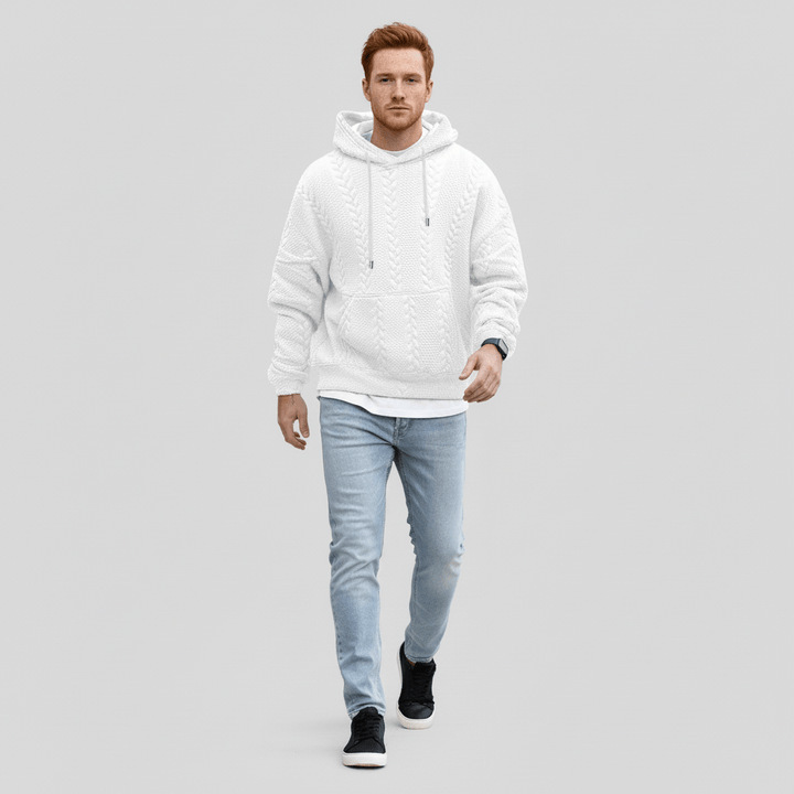 Mann spaziert im Logan Zopfmuster Kapuzenpullover. Lässiger Strick Hoodie, perfekt für Herbst & Winter.