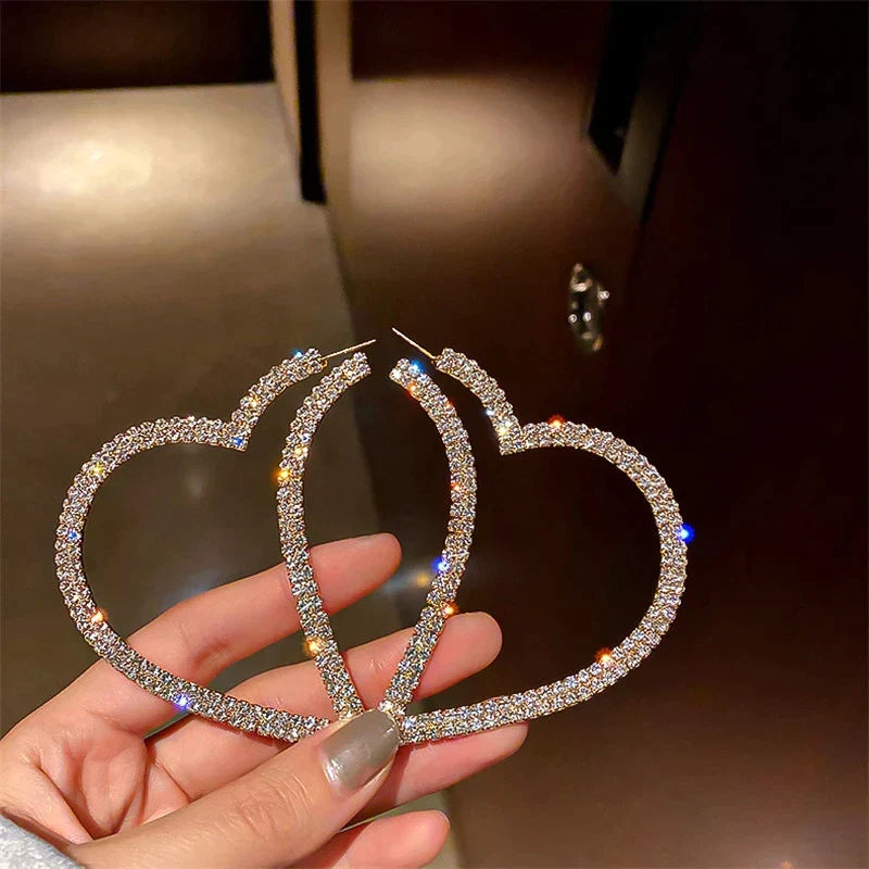 Detailaufnahme von glänzenden Herzohrringen mit funkelnden Kristallen, edler Damenschmuck.