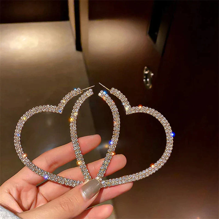 Detailaufnahme von glänzenden Herzohrringen mit funkelnden Kristallen, edler Damenschmuck.