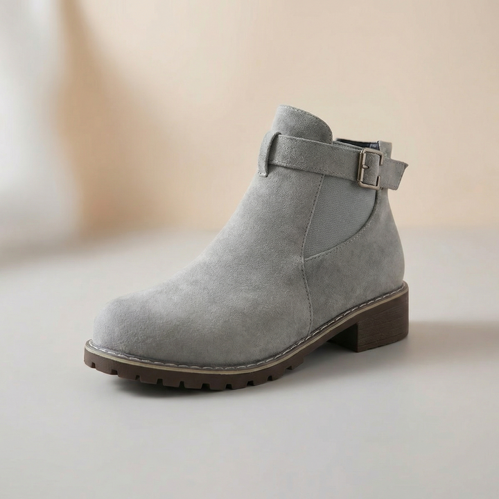 Seitenansicht: Grau-braune Damen Stiefeletten aus Wildleder-Optik, mit verstellbarer Schnalle & niedrigem Blockabsatz.