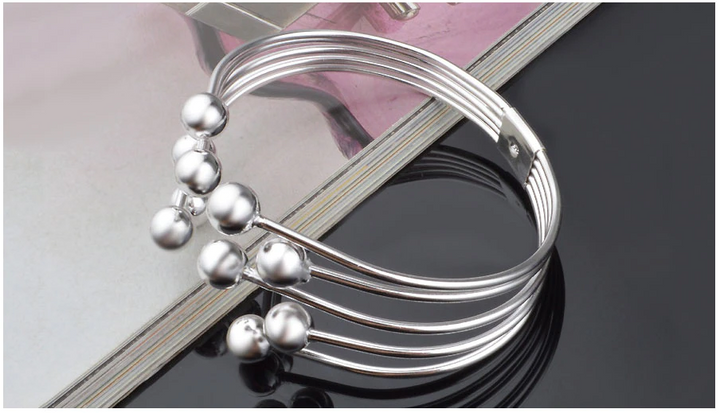 Damen Silberarmband mit glänzenden Perlen, offenes Design. Verstellbares Schmuckstück und schönes Accessoire.