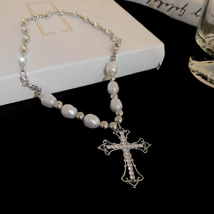 Detailaufnahme einer Damen Perlenkreuz Halskette: filigraner Anhänger & glänzende Perlen. Damenschmuck.