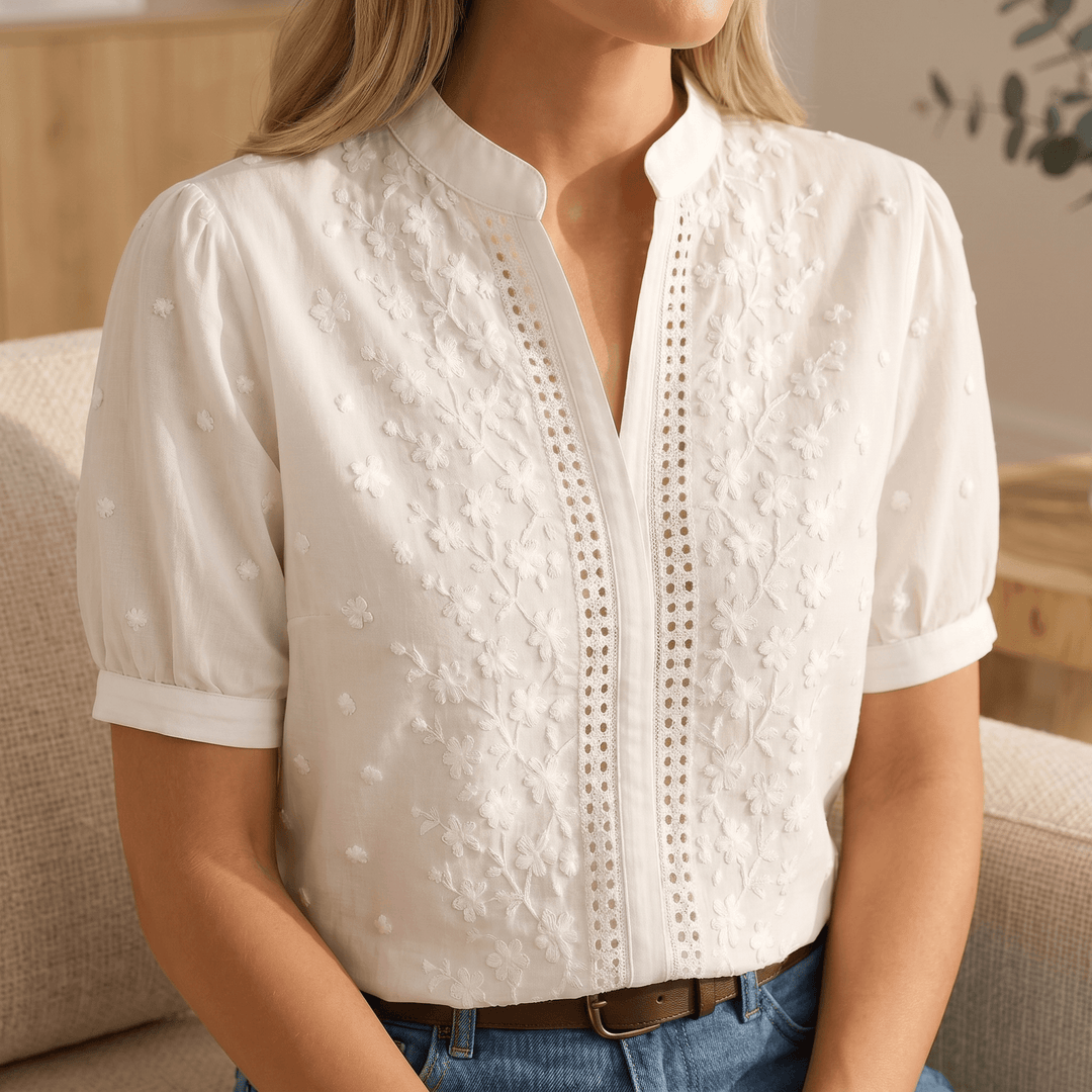 Detailaufnahme: Florale Stickerei auf eleganter weißer Damenbluse, frühlingshaftes Design.