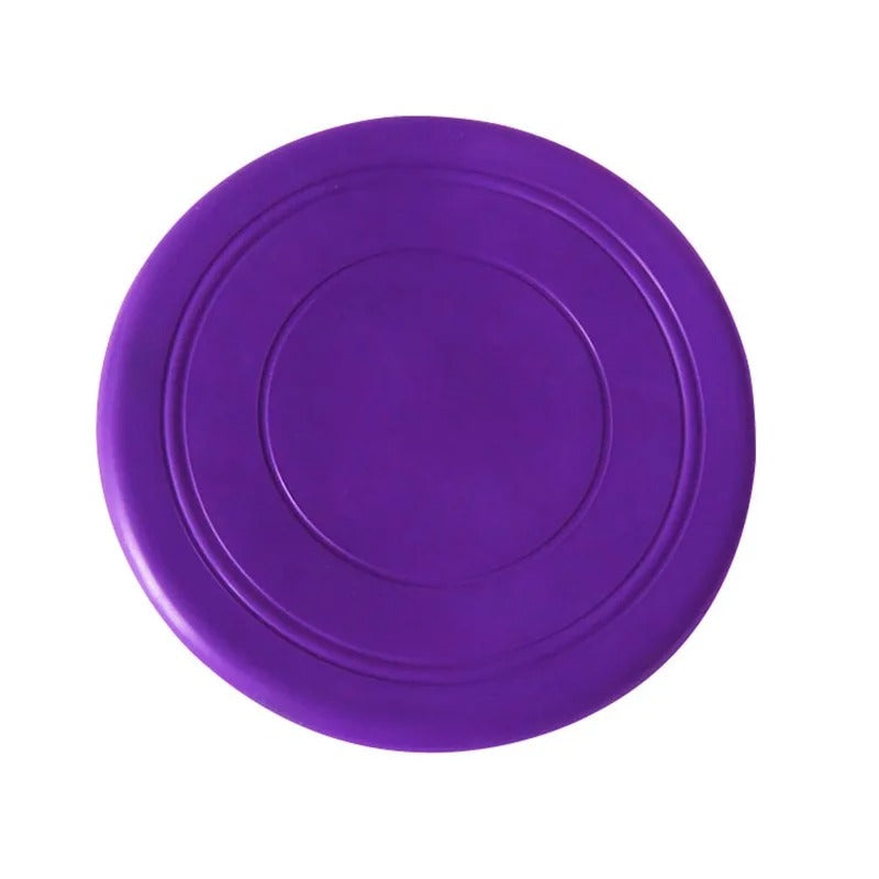 Ein Hund fängt eine leuchtend farbige Silikon-Frisbee im Park; robustes Outdoor-Hundespielzeug.