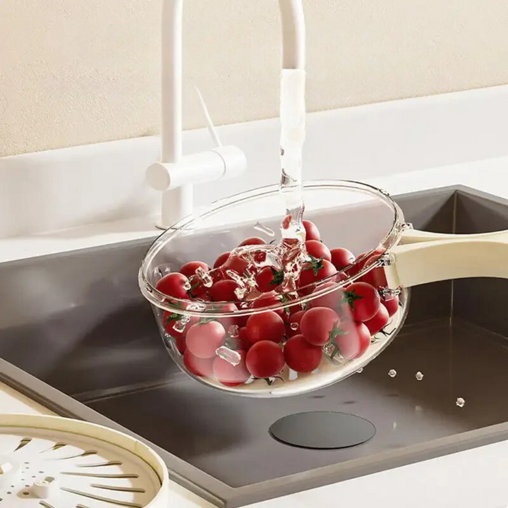 Nahaufnahme einer Person, die frisches Obst in der multifunktionalen Abtropfschale mit Sieb wäscht.