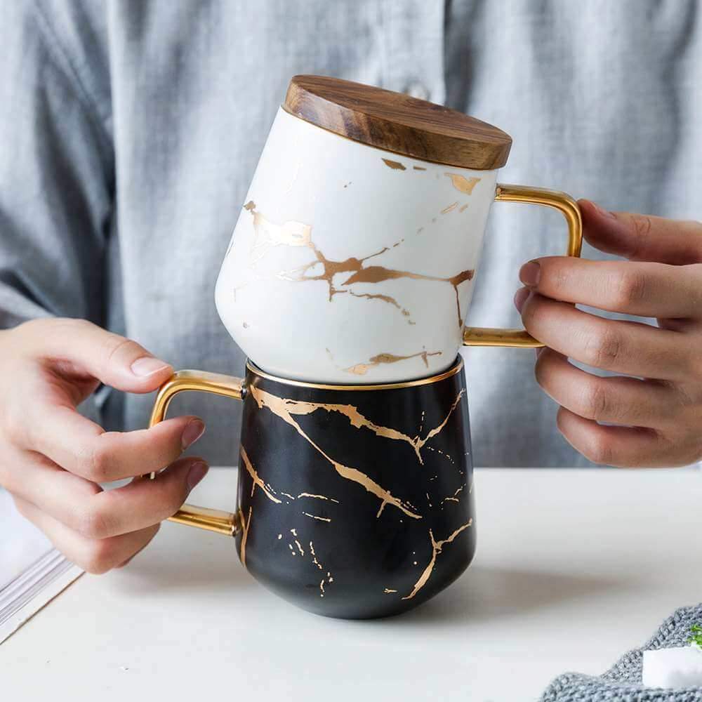 Eine gefüllte Teetasse im Kintsugi Stil, nordische Keramik, Schwarz/Weiß, mit goldenen Akzenten für Genuss.