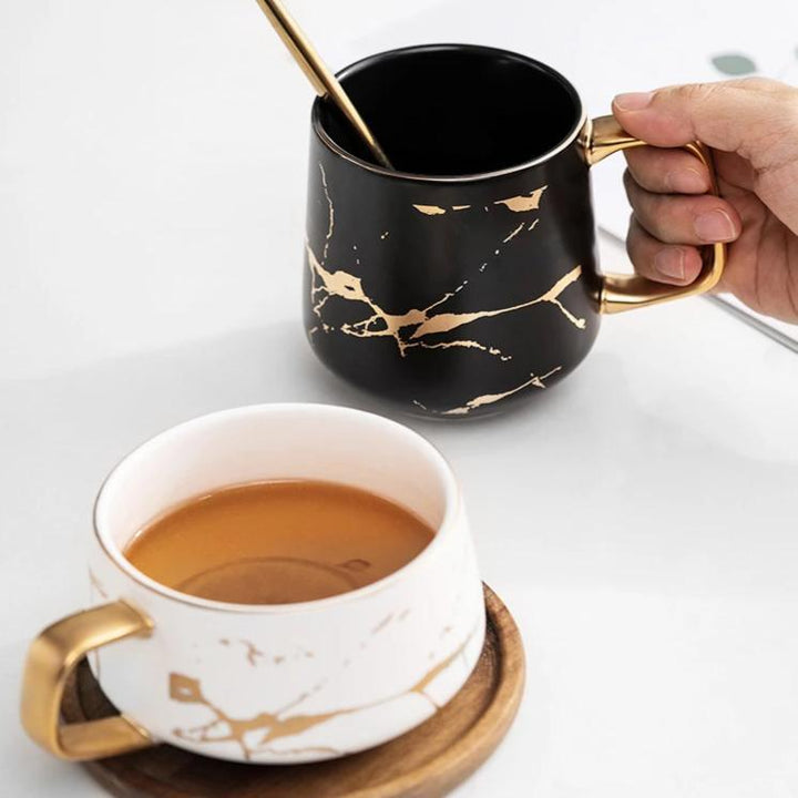 Einzigartige Kintsugi Keramik Tasse, nordisch inspiriert, schwarz-weißes Design mit edlem goldenem Muster.