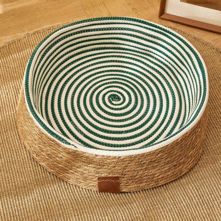 Naturmaterial Rattan: Braun-dunkelgrünes Katzen-Kratzbett, handgeflochten, stilvolles Wohnaccessoire.