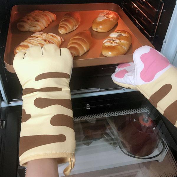 Stylische Katzenpfoten Ofenhandschuhe beim Herausnehmen von heißem Geschirr aus dem Ofen.