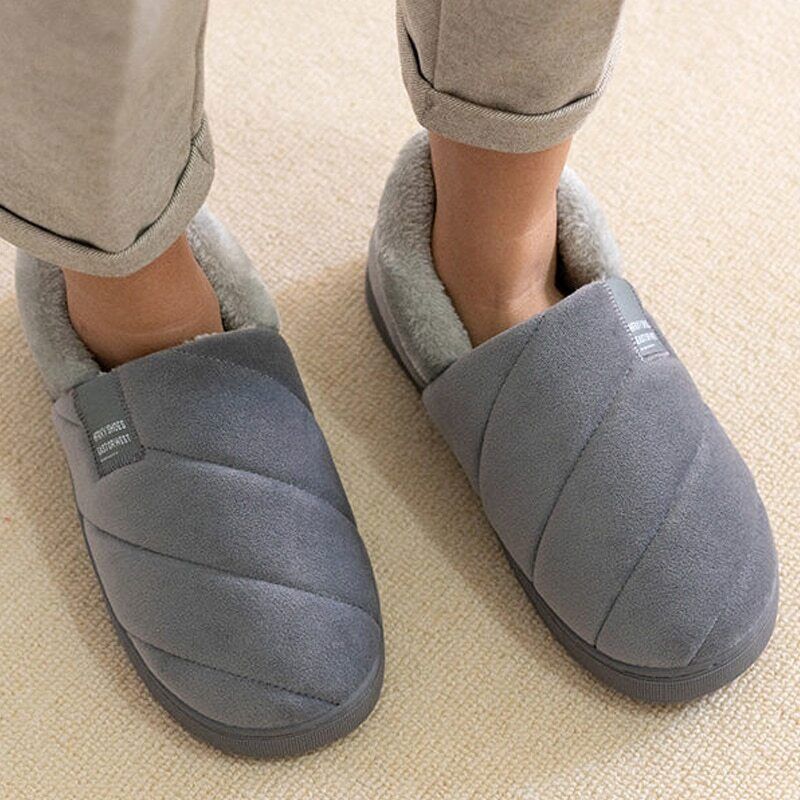 Ein Paar warme Moccasin-Hausschuhe an Füßen, bereit für gemütliche Herbst- und Winterabende.