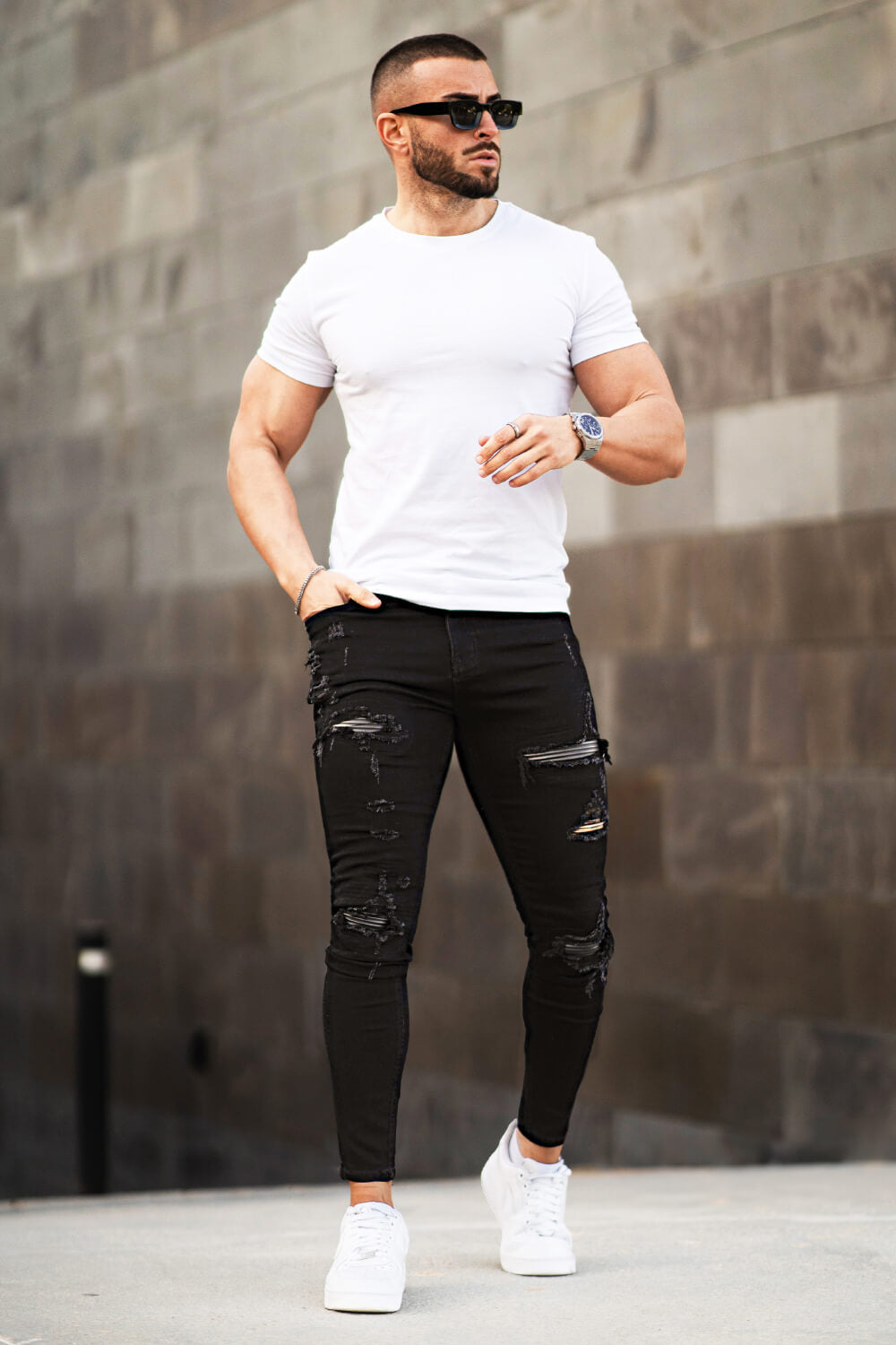 Detailaufnahme der schwarzen Herrenjeans mit stylischen Zerrissen-Details am Knie.