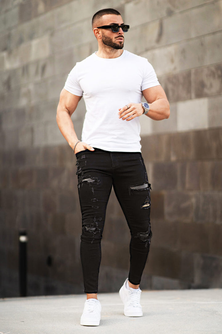 Detailaufnahme der schwarzen Herrenjeans mit stylischen Zerrissen-Details am Knie.