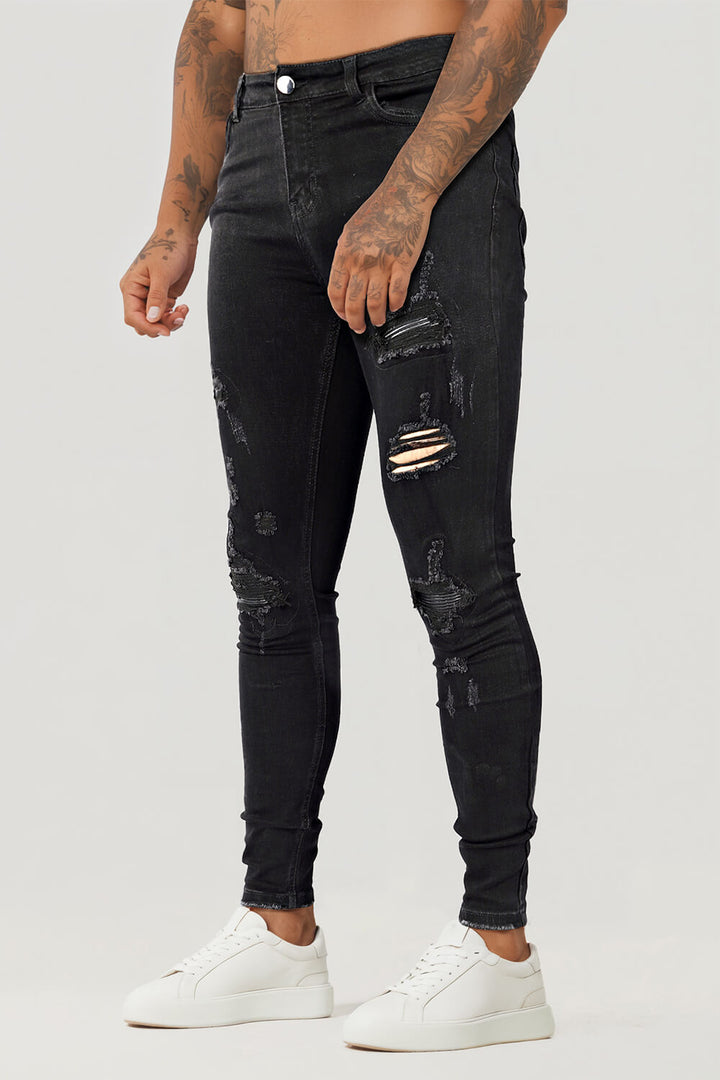 Moderner Mann trägt schwarze zerrissene Skinny Jeans; stylische Herrenmode für urbane Looks.