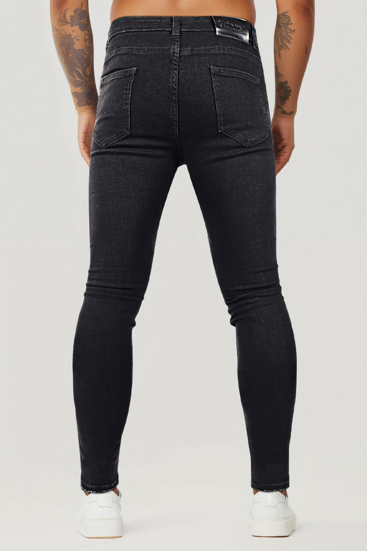 Nahaufnahme der Stofftextur der schwarzen Skinny Jeans für Herren, zeigt authentische Destroyed-Effekte.