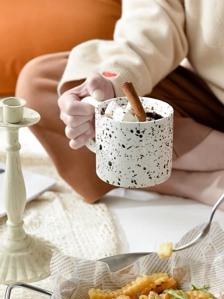 Weiße Keramiktasse mit schwarzen Punkten, komfortablem Griff – ideal für Tee oder Kakao.