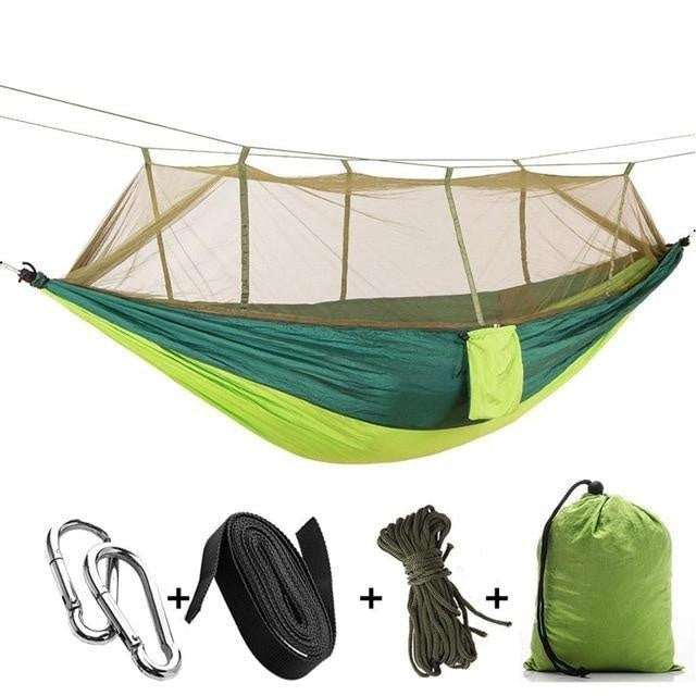 Person entspannt in der Camping-Hängematte mit Mückennetz, geschützt vor Insekten im Freien.
