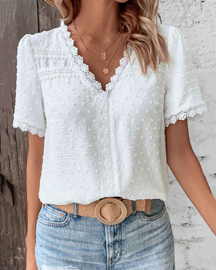 Leichte weiße Damen Sommerbluse mit V-Ausschnitt, kurzen Ärmeln und dezentem Patchwork-Muster. Vielseitiges Oberteil.